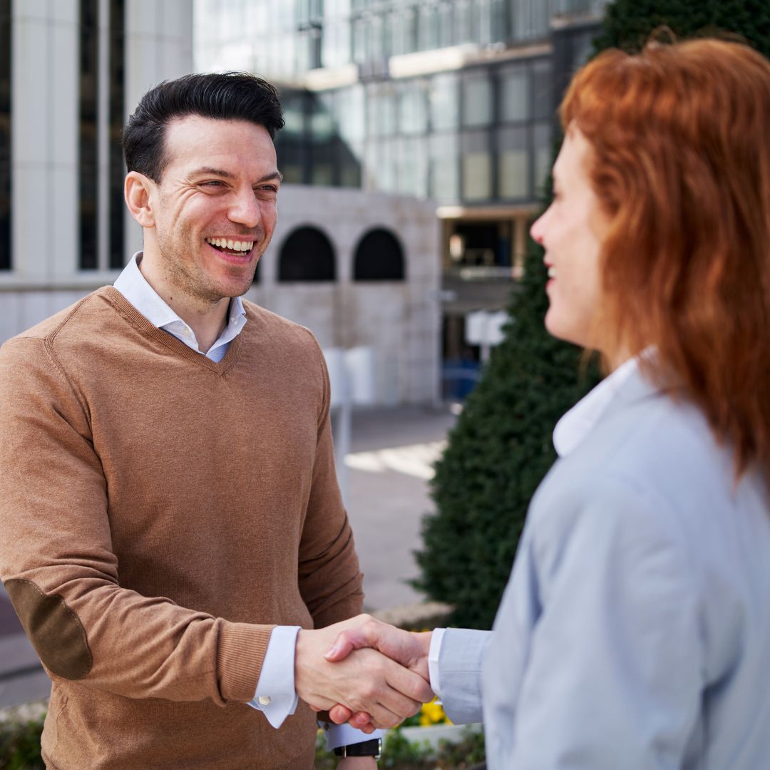 Dwóch biznesmenów w garniturach negocjuje ceny przy stole z dokumentami i laptopem
