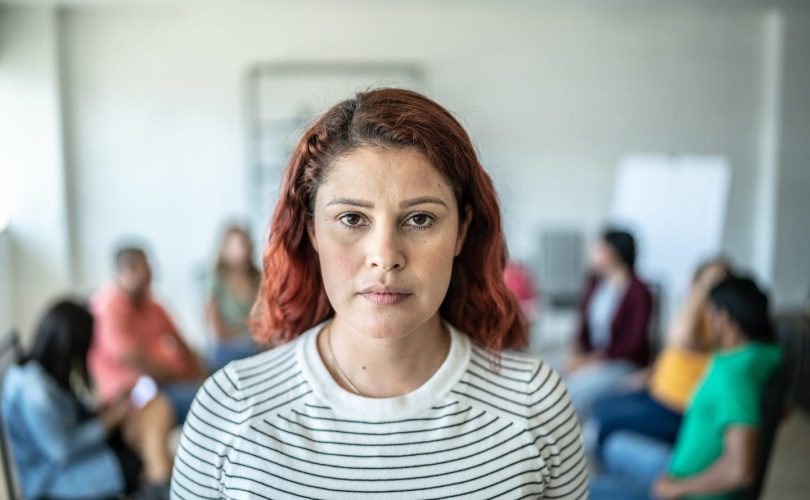 Młody przedsiębiorca drapie się po głowie przy biurku z laptopem i spadającymi wykresami